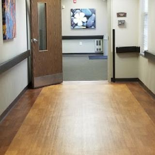 A tranquil hospital hallway showcasing wooden flooring and artwork on the walls.
