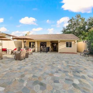 A spacious backyard with a tiled patio and outdoor furniture under a bright blue sky.