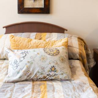 A cozy bedroom setting featuring a beautifully arranged bed with patterned bedding and decorative pillows.
