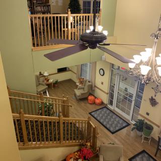 A spacious open-plan living area with a ceiling fan, staircase, and cozy seating.