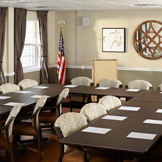 A well-organized conference room with tables, chairs, and a podium, featuring an American flag and decor elements.