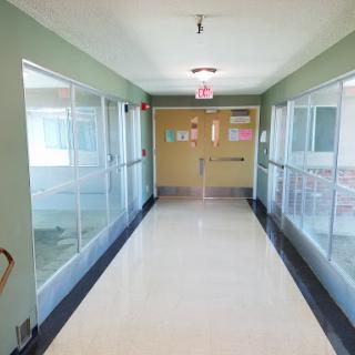A bright and spacious hospital hallway with green walls and glass partitions.