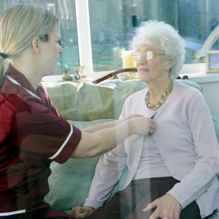 A nurse conducting a medical check-up for an elderly woman at home.