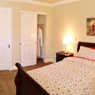 A cozy bedroom with a neatly made bed, nightstand, and closet.