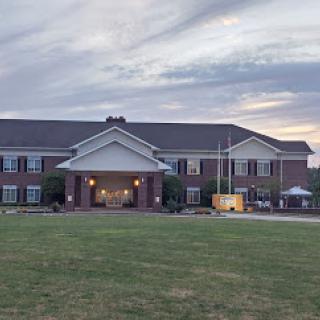 A welcoming residential building at dusk, featuring a broad lawn and an inviting entrance.