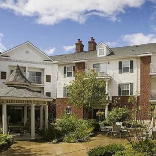 A charming residential building with a well-maintained garden under a clear blue sky.