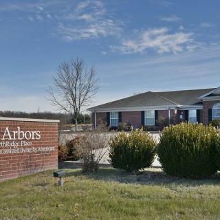 A nursing home facility with a landscaped entrance sign on a sunny day.