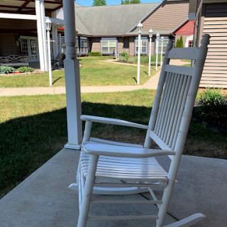 A white rocking chair on a sunny porch, inviting moments of relaxation.