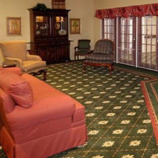 A cozy living room with a sofa, armchair, and patterned carpet.