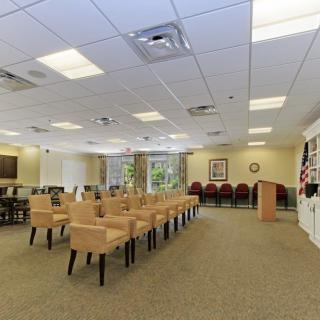 A spacious room with rows of chairs, a podium, and bright lighting.