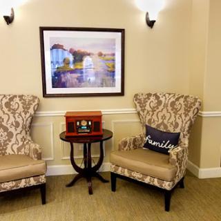 A cozy corner featuring elegant chairs, a small side table, and a beautiful piece of wall art.