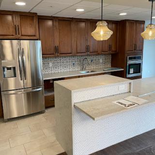 A modern kitchen featuring wooden cabinets, stainless steel appliances, and an elegant island with pendant lighting.