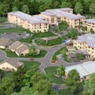 Aerial view of a building complex surrounded by greenery and roads.