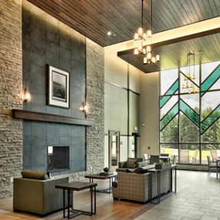 A spacious and elegantly designed lobby featuring a modern fireplace, comfortable seating, and large stained glass windows that allow natural light to flood the space.