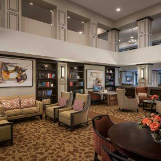 A cozy lobby area with comfortable seating, bookshelves, and artwork on the walls.
