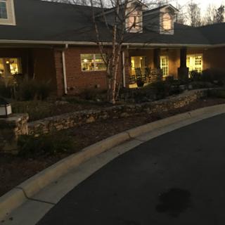 A cozy house illuminated in the evening, showcasing its landscaped front yard.