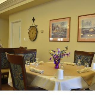 A neatly arranged dining room table with elegant decor and artwork on the walls.