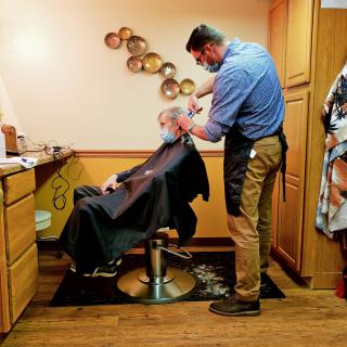 A barber giving a haircut to a client in a barbershop.