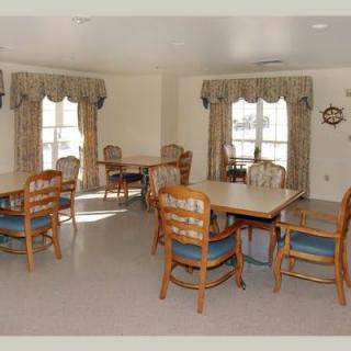 A spacious dining area with multiple tables and chairs, featuring large windows with curtains.