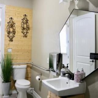 A well-decorated bathroom featuring a hexagonal mirror, a sink, and wall art.