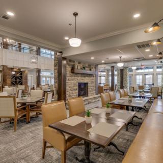 A modern restaurant dining area with elegant tables and chairs, featuring a central fireplace and ambient lighting.