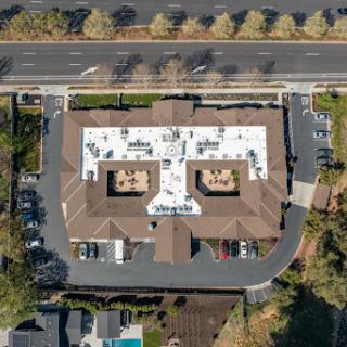 An aerial view of a building featuring multiple rooftop areas and surrounding parking.