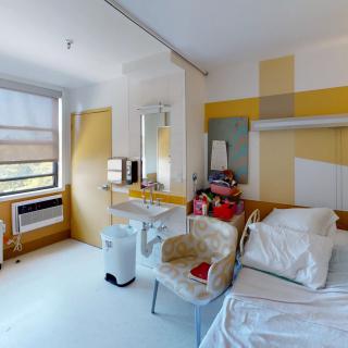 A clean and modern hospital room with a bed, sink, and window.