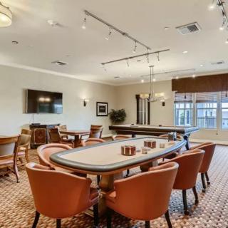 A well-furnished conference room featuring a large table surrounded by chairs, with a television mounted on the wall.