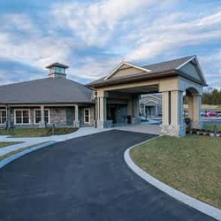 A modern building with a curved driveway under a partly cloudy sky.