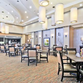 A spacious and elegantly decorated restaurant dining area with multiple tables and chairs.
