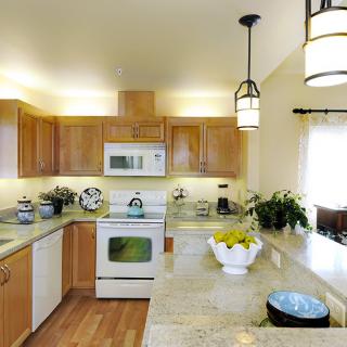 A modern kitchen with wooden cabinets, granite countertops, and sleek appliances.