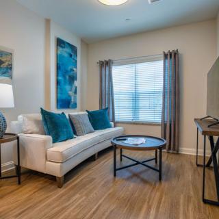 A modern living room with a comfortable sofa, elegant artwork, and ample natural light.