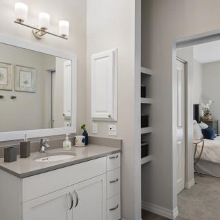 A modern bathroom featuring a white vanity with a large mirror and contemporary lighting.