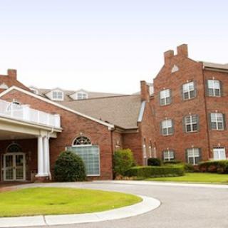 A view of a brick residential building with a welcoming entrance and landscaped grounds.