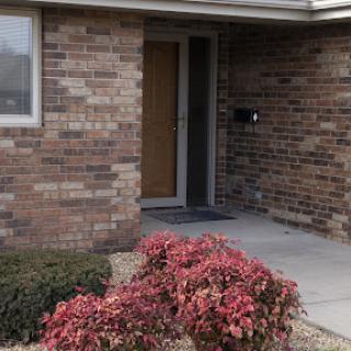 A welcoming entrance with brick walls and colorful plants.