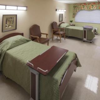 A clean and neatly organized hospital room with two beds and medical equipment.