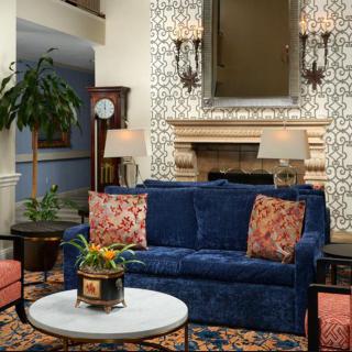 A stylish living room with a blue sofa, ornate wall decor, and cozy fireplace.