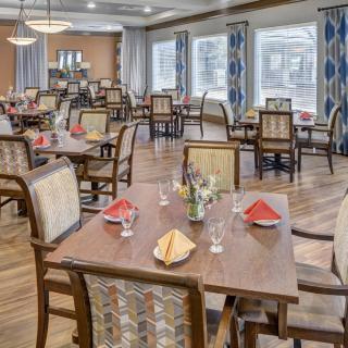 A well-arranged dining room with several tables and chairs, featuring elegant place settings.
