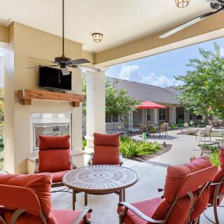 A cozy outdoor patio with red-cushioned seating, a table, and a garden view.