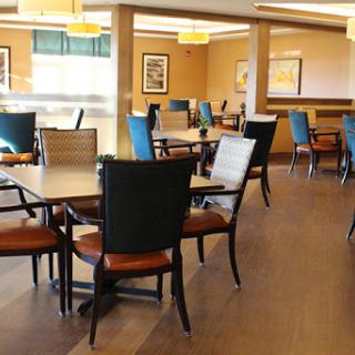 A spacious and inviting dining area with neatly arranged tables and chairs, featuring a warm color palette and modern decor.