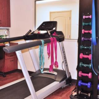 A home gym setup featuring a treadmill, dumbbells, and resistance bands.