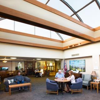 A well-lit lobby with a skylight where people are seated and engaged in conversation.