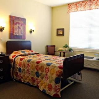 A cozy bedroom with a single bed, colorful bedding, and wall art.