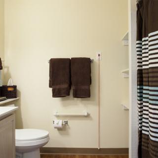 A clean bathroom with towels, a toilet, sink, and a patterned shower curtain.