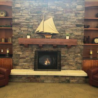 A cozy living room with a stone fireplace and sailboat decor.