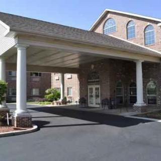 A brick building with a grand entrance featuring large white columns and an overhang.
