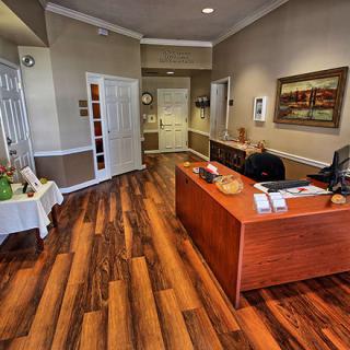 A welcoming office reception area with a desk and wood flooring.