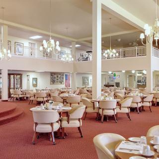A spacious dining area with elegant chandeliers and arranged tables and chairs.