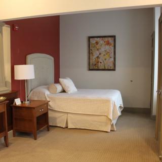 A cozy hotel room with a neatly made bed, nightstands, and ambient lighting.