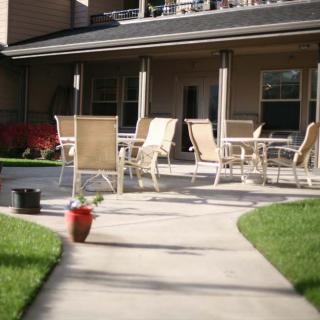 A patio with outdoor seating surrounded by a well-maintained lawn and potted plants.